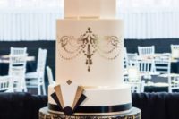 08 a large round wedding cake with gold and black lace decor, gold and black geo decorations and ribbons