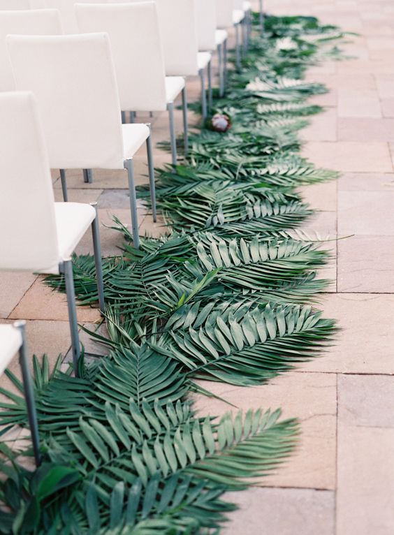 a palm leaf lined wedidng aisle for a modern wedding ceremony space