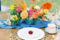 The tablescape was done with a bold blue table runner, dip dye napkins, wicker chargers, a sparkly blue vase with bold blooms