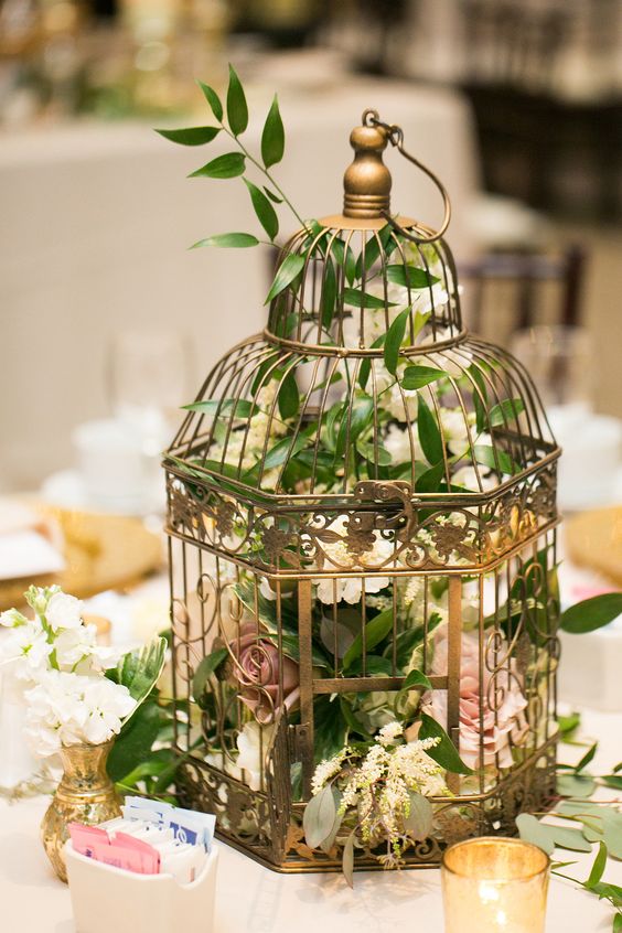 a metallic cage with foliage and lush florals for a beautiful wedding centerpiece