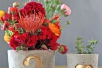 11 pots with gilded table numbers and a heart and filled with blooms