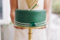 12 a round wedding cake with a white lace and an emerald lyaer with gold details, pearls and an emerald