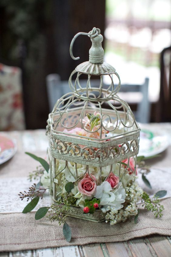 a shabby chic bird cage with white, pink and blush florals