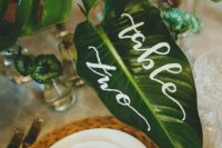 13 hand-lettered tropical leaf table number and place cards for a tropical wedding