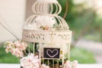 14 a small cage with a chalkboard sign, pink blooms and greenery