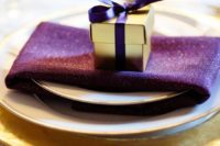 15 a place setting with a gold charger and cutlery, a purple napkin and a gold and purple favor box