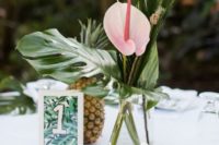 15 a tropical wedding centerpiece with a bold pink flower, a tiny pineapple skewer