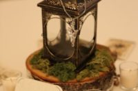 15 a wedding centerpiece of a wood slice, moss, a vintage lantern and Arwen’s necklace