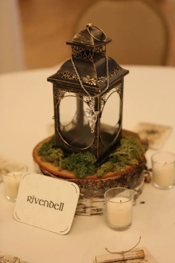 a wedding centerpiece of a wood slice, moss, a vintage lantern and Arwen's necklace