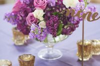 16 a lush floral centerpiece in the shades of lilac, purple and cream and gold candle holders