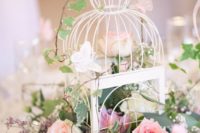 16 a small white birdcage with lush greenery and white and pink blooms