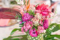 16 a tropical wedding centerpiece of a pineapple with bold pink blooms displayed on a tropical leaf