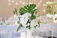 17 a wedding centerpiece with palm leaves, white blooms and lush orchids