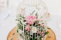 17 a white cage on a wooden slice with pink and white blooms inside for a rustic wedding