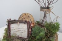 17 a wood slice with moss and a succulent, stone, a vase with branches and a framed quote for a centerpiece