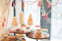 the assortment of wedding cakes and desserts are accentuated with ropes with colorful tassels