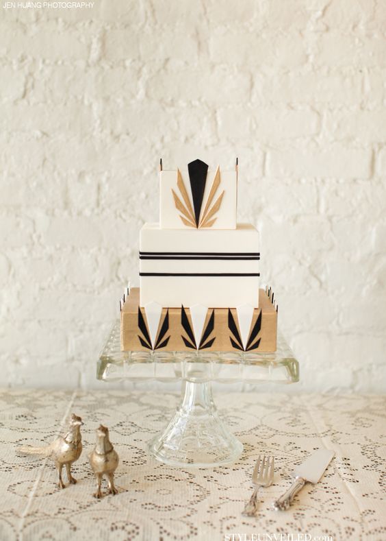 a square wedding cake with black and gold geometric decor
