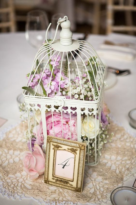 a white cage with lush florals of white, pink and lilac color for a sweet vintage wedding