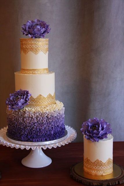a chic wedding cake with an ombre purple ruffle layer, white layers with gold lace decor and purple flowers