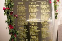 20 an oversized mirror seating chart with gold calligraphy, red roses and greenery