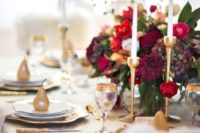 21 gold candle holders, gold rim glasses and red florals for a gorgeous wedding tablescape