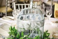 22 a birdcage surrounded with lush foliage for a chic and non-typical wedding centerpiece