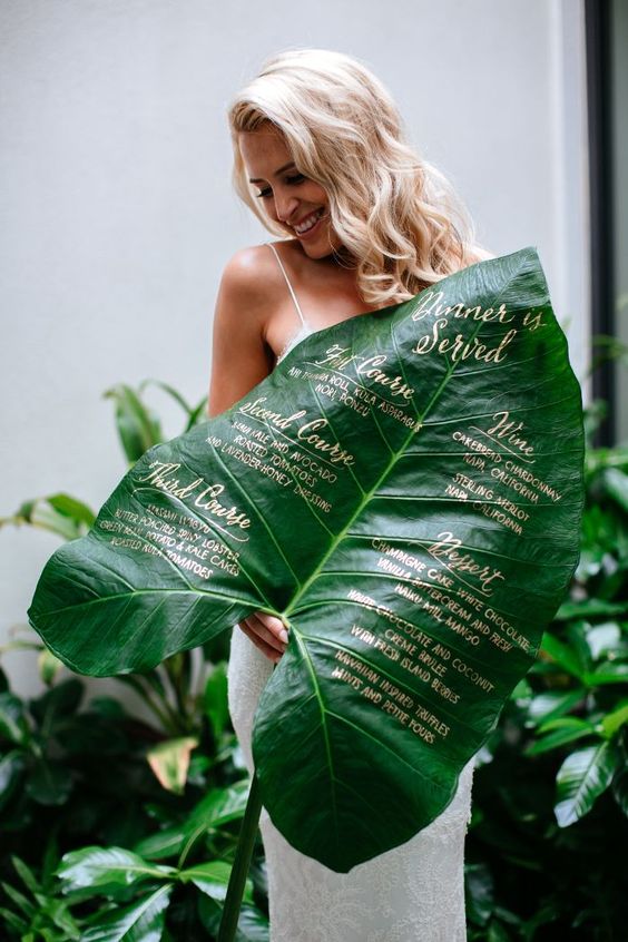 a stunning wedding menu with gold calligraphy on an oversized leaf
