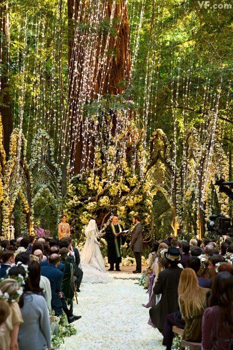 unique elf inspired ceremony space with giant trees, lots of greenery, flowers and moss, the aisle covered with petals completely