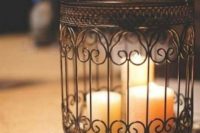 24 a black birdcage used as a large candle holder for several candles