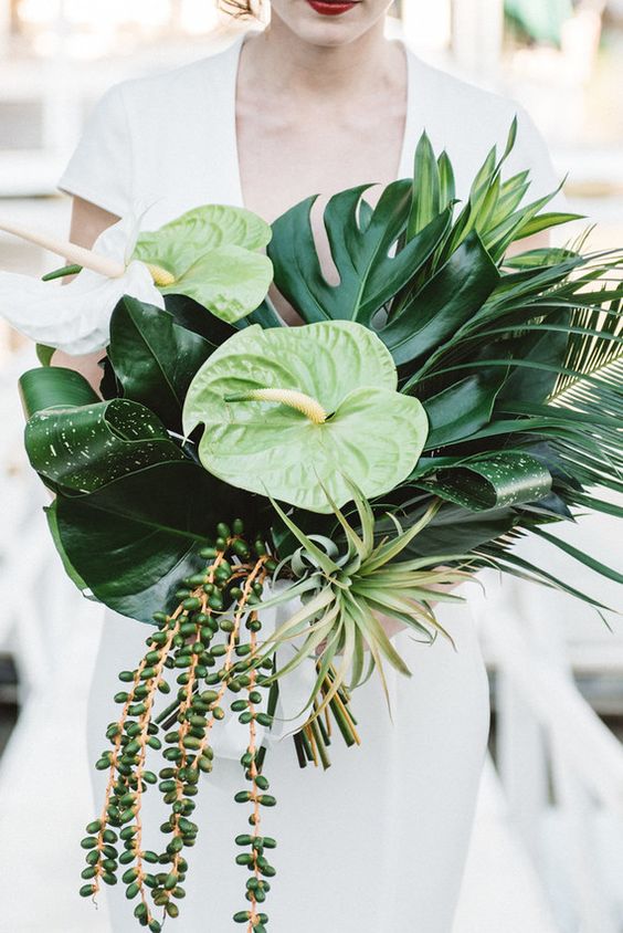 a bold tropical wedding bouquet with tropical leavs, blooms and hanging succulents