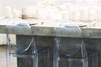 25 a concrete dining table with lots of candles and acrylic chairs are a great combo for a minimalist wedding