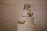 26 a textural white wedding cake with gold snitches and a cake topper