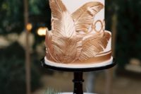27 a wedding cake with gold tropical leaves and stripes for an elegant look