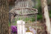 28 a vintage birdcage with moss and purple and lilac blooms can be suspended over the reception