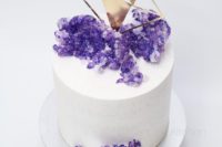 28 a white wedding cake with a gold diamond topper and purple sugar amethysts