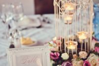 31 a white cage with tealights and bold blooms that surround the cage