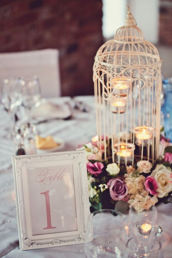 a white cage with tealights and bold blooms that surround the cage