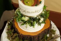 a LOTR wedding cake with greenery, a hobbit house on top and a tree slice as a stad is a perfect LOTR wedding idea