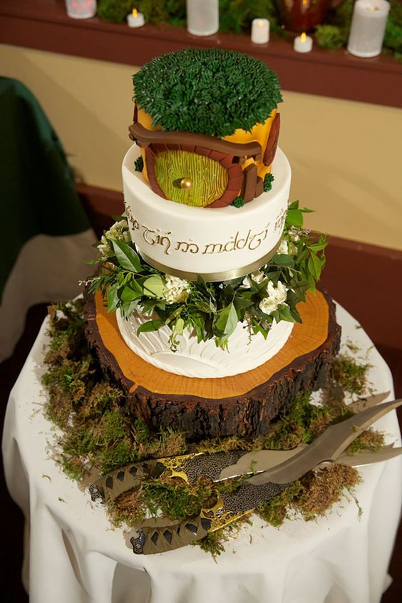 a LOTR wedding cake with greenery, a hobbit house on top and a tree slice as a stad is a perfect LOTR wedding idea