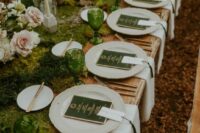 a LOTR wedding tablescape with a moss runner, greenery, blush roses, green glasses and green menus plus gold cutlery