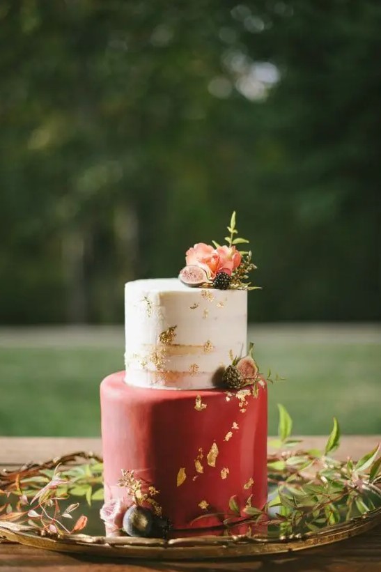 a beautiful and chic wedding cake with a naked and a red tier with gold leaf, with pink blooms, berries and a bit of greenery is a refined idea for a fall wedding