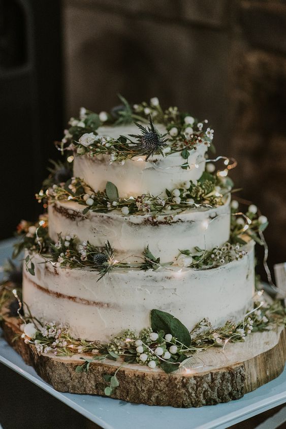 a beautiful naked wedding cake with greenery, berries and thistles, LEDs is a cool idea for a LOTR wedding