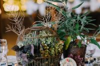 a beautiful rustic wedding centerpiece of tree slices, a cage with greenery and leaves and potted plants