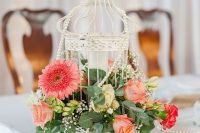 a beautiful white cage with coral, pink and yellow blooms, greenery and baby’s breath is amazing