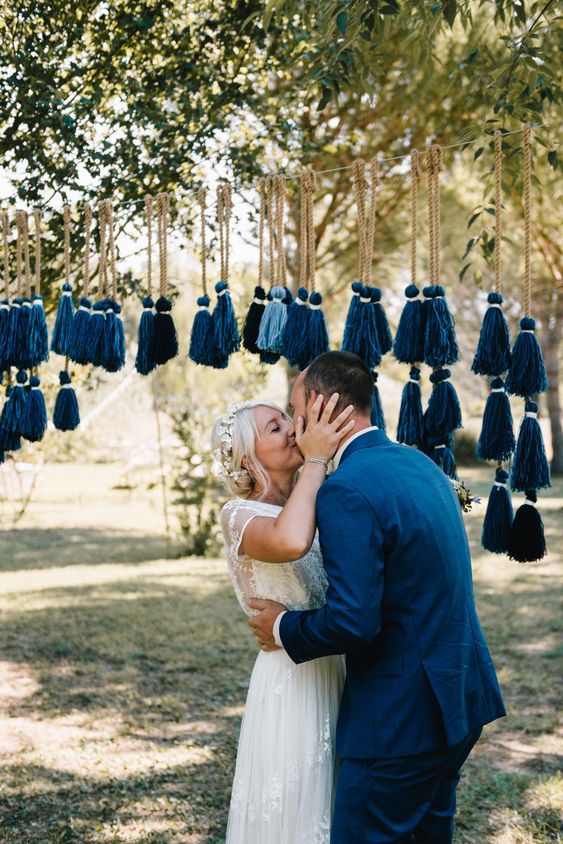 a boho wedding backdrop of light blue and navy tassels on rope is a fun and cool idea for both indoor and outdoor wedding