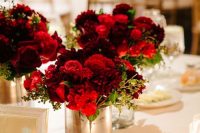 a bold and catchy wedding centerpiece of a vase with lush red blooms and greenery is amazing for a bold wedding