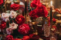 a bold modern wedding tablescape with a gold charger and cutlery, red roses and blush ones, black candles is amazing