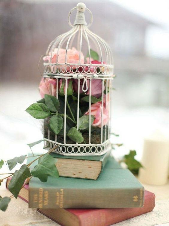 a book stack with a cage, moss, blooms and greenery is a lovely book lover wedding idea