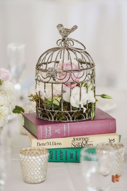 a book stack with a shabby chic cage, blush and white blooms and greenery is a chic vintage wedding idea