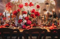 a bright and catchy wedding table setting with black, red and pink roses, red napkins and black candles is wow